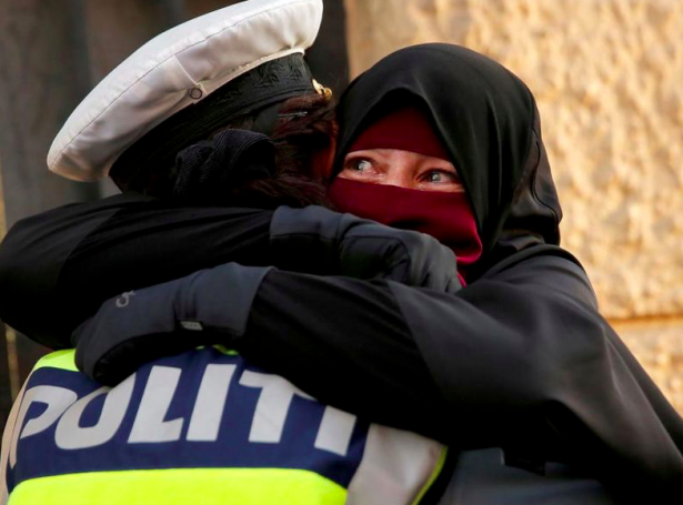 Ein løgreglukvinna klemmaði eina kvinnu í niqab, tá fólk mótmæltu maskuforboðið í summar (Mynd: Reuters)