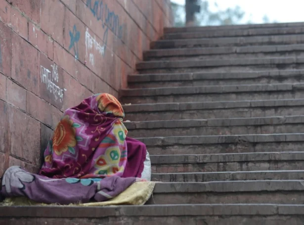 Heimleysur maður fjalir seg undir einum teppi í kuldanum í New Delhi, India (Mynd: EPA)