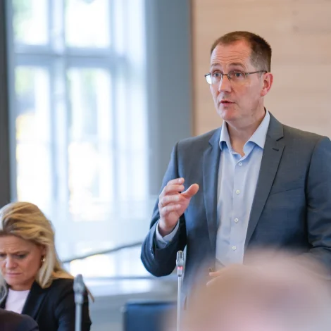 Dennis Holm situr báðu megin borðið