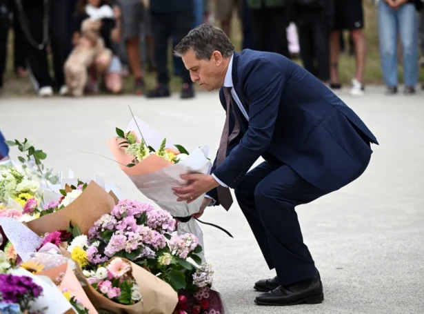 Ryan Park, heilsumálaráðharri í statinum New South Wales leggur blómur til minnis um tey, sum lótu lív í álopinum sunnudagin (Mynd: EPA)
