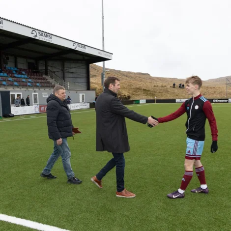 Tað var pápi Sjúrð, Rói Henriksen, saman við Sjúrði Olsen, stjóra í Bygma Balslev, og Hera á Rógvi, starvsnevndarlimi í FSF, sum vegna Fótbóltssamband Føroya handaðu Sjúrði Henriksen eitt gávubræv uppá 1.000 krónur frá Atlantic Airways, og eina heiðursplátu, ið er latin av FSF (Mynd: Finnur Justinussen/fsf.fo)