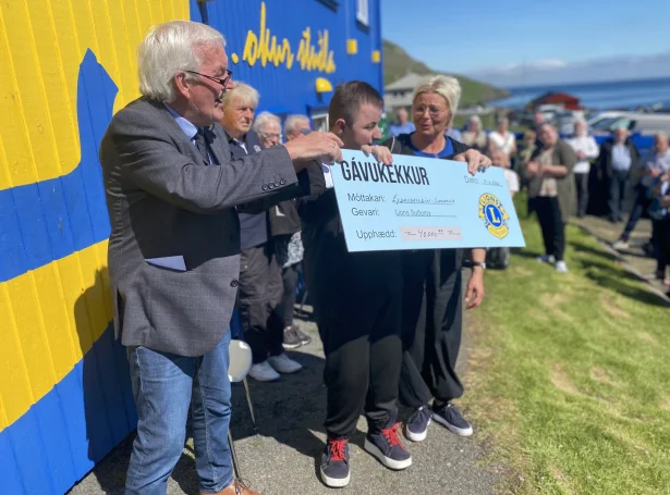Bent Albinus, forseti í Lion Suðuroy, handar Markusi Midjord og mammu hansara, Vár Mortensen, gávukekkin upp á 40.000 krónur frá Lions Suðuroy í góðveðrinum uttan fyri Lions húsið í Hovi