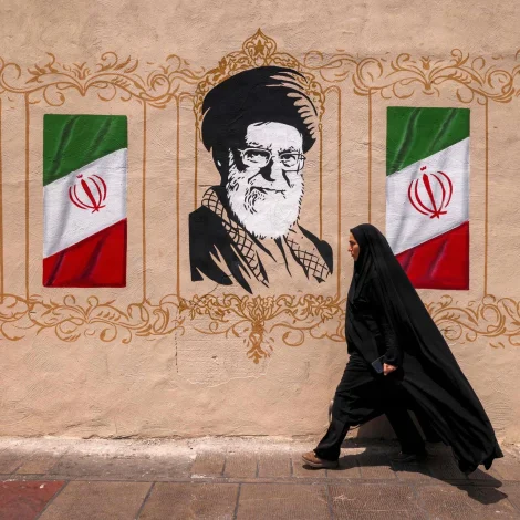 Iransk kvinna gongur framvið veggmálningi av fyrrverandi leiðaranum í Iran, Ali Khamenei (Mynd: Atta Kenare/AFP/Ritzau Scanpix)